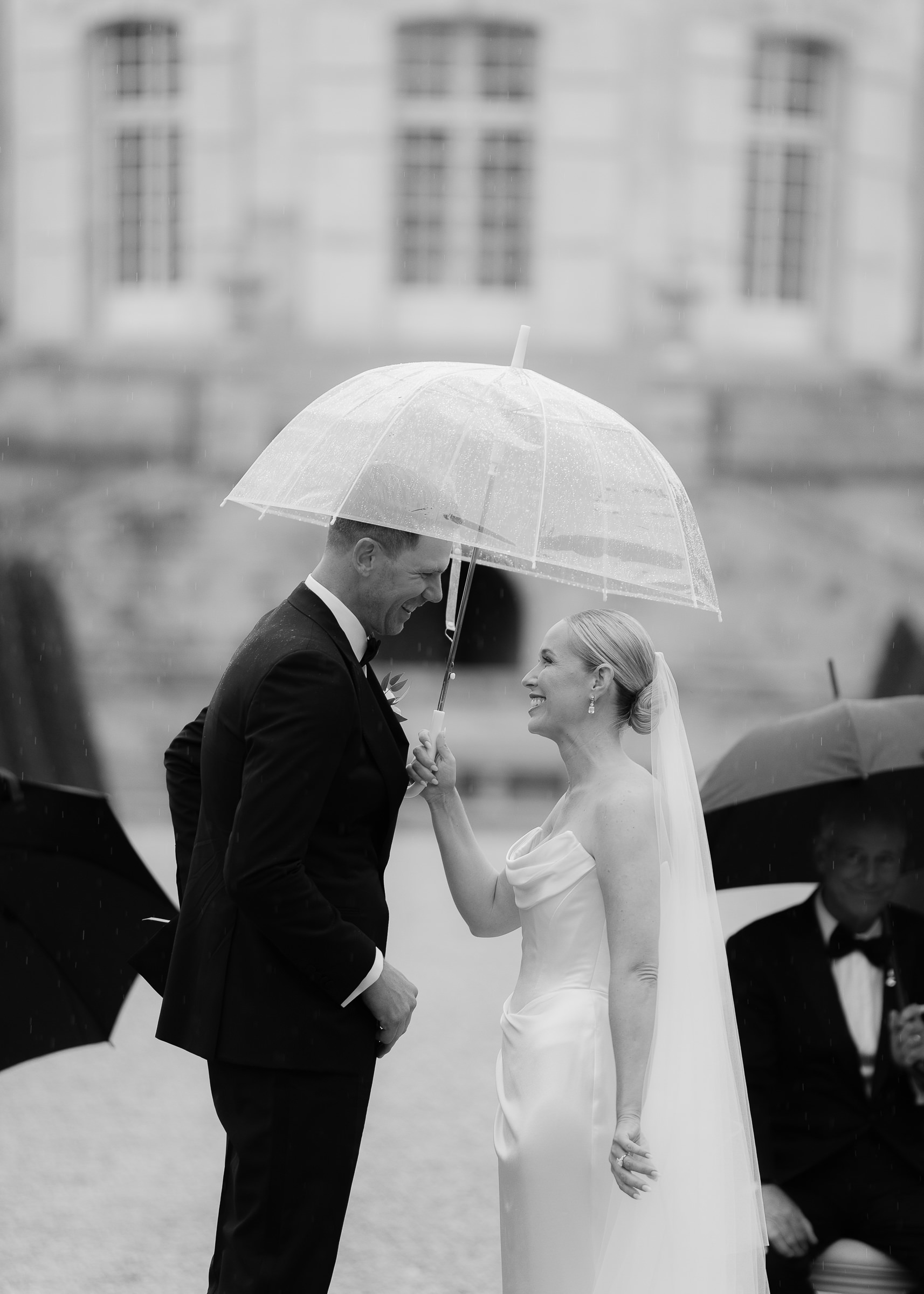 Bride and groom smiling as soft rain falls during vows at Château Villette