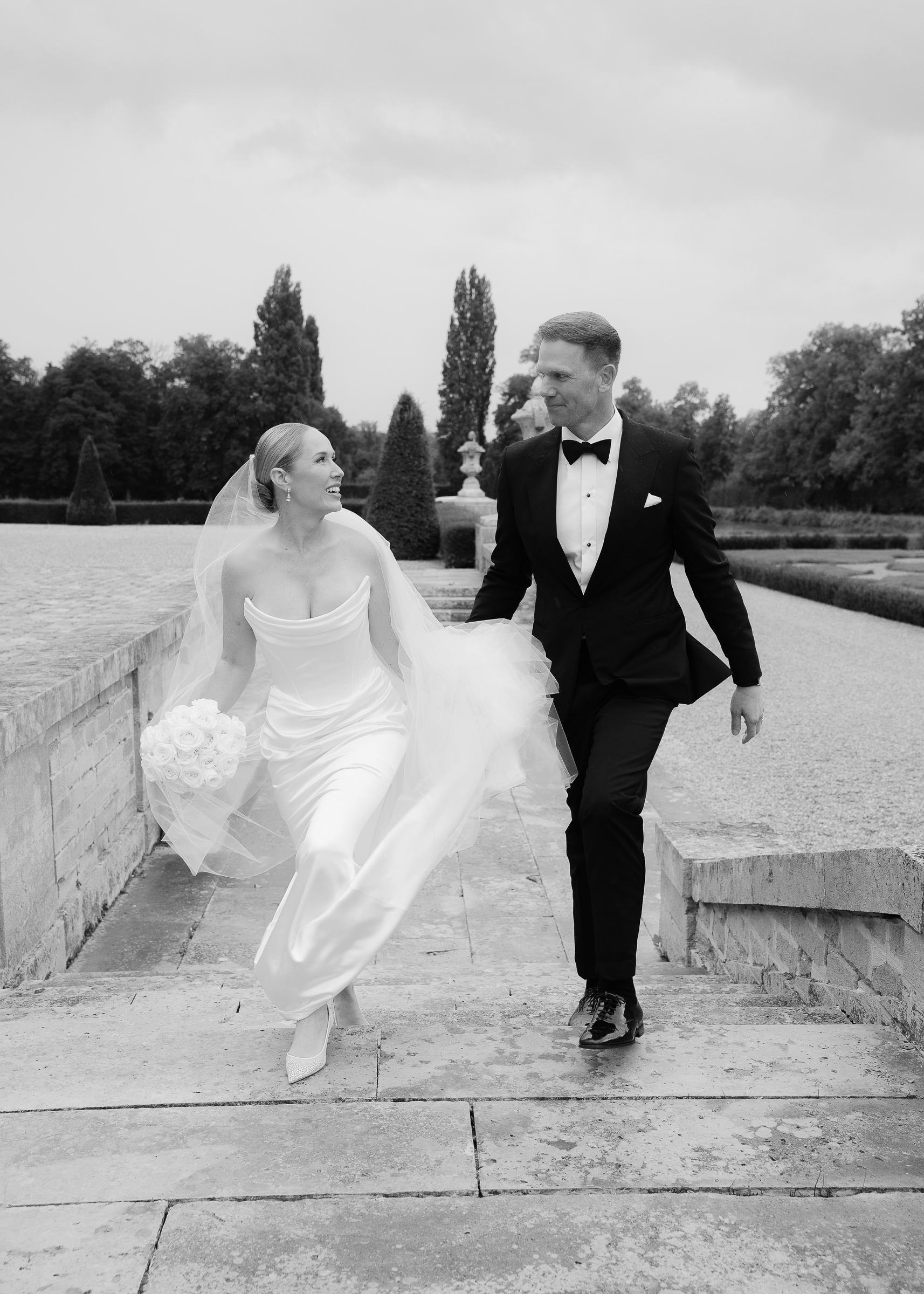 Bride and groom walking hand in hand through Château Villette’s French gardens