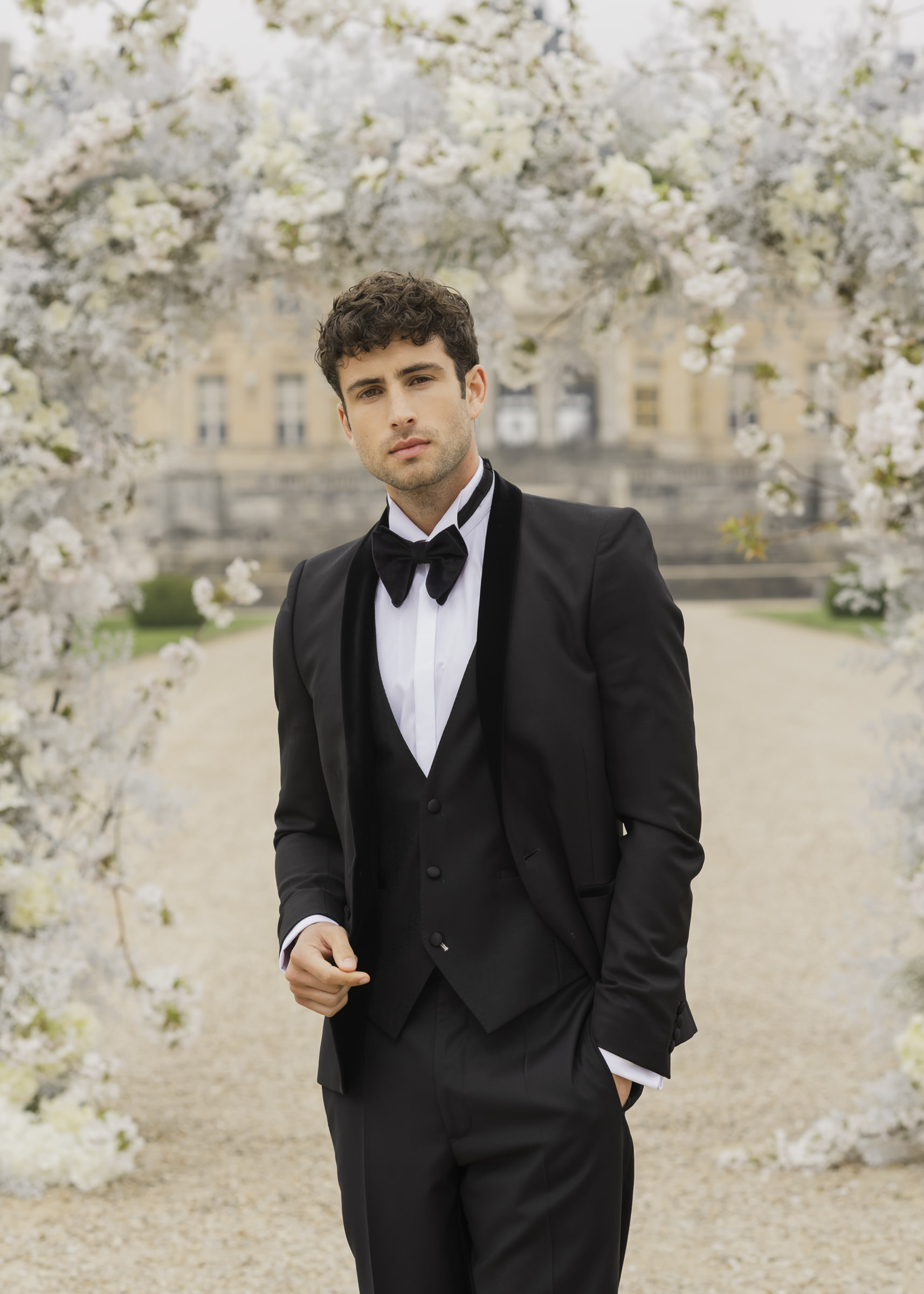 Luxury ceremony setting with groom portrait beneath a modern floral arch
