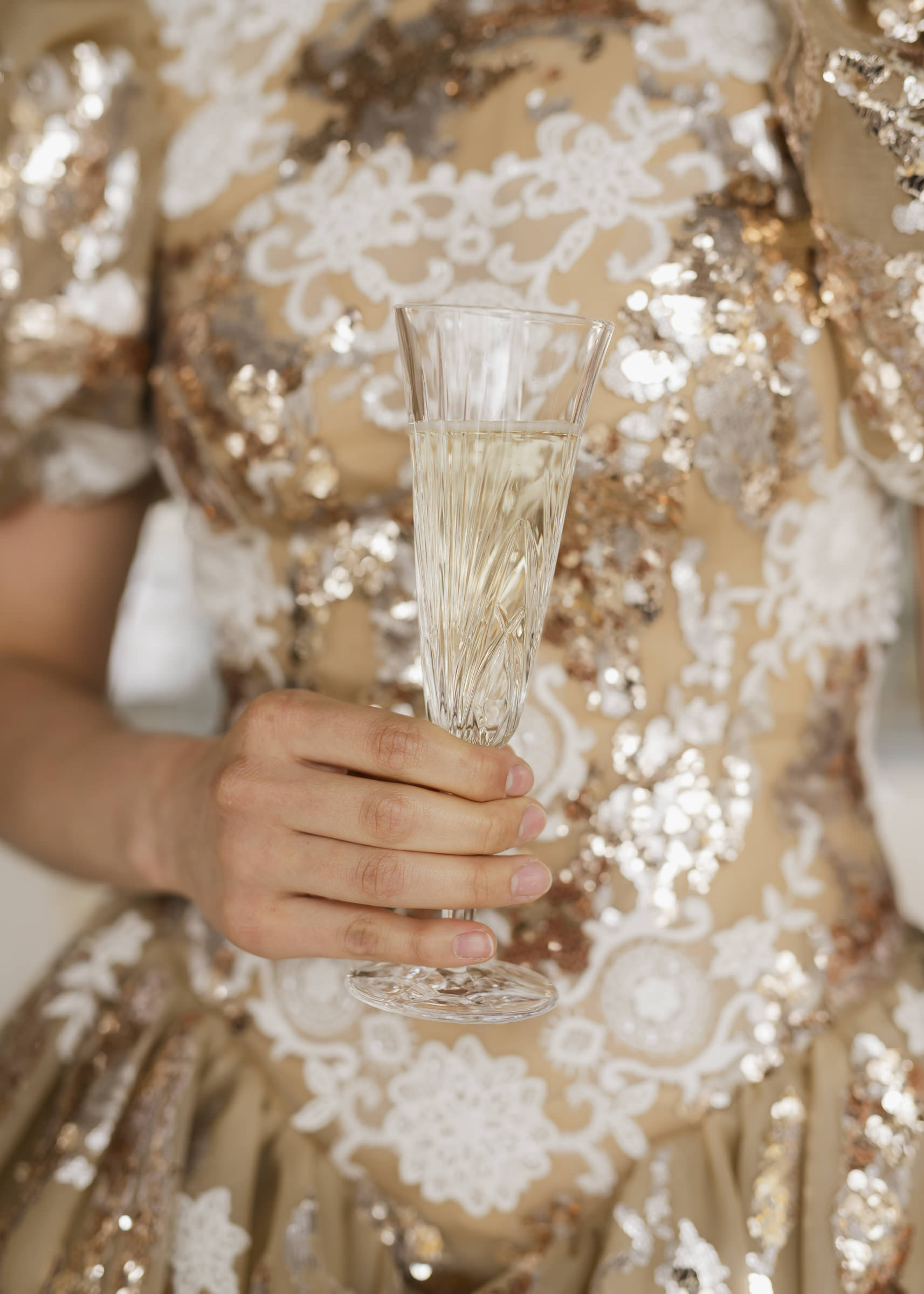 Detail of couture bridesmaid dress with champagne showcasing luxury fabric.